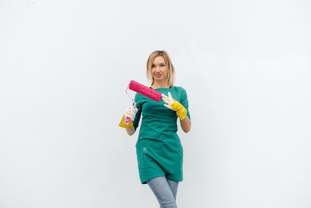 Une jeune fille pose avec un rouleau rose avant de peindre un mur blanc. Réparation de l'intérieur.