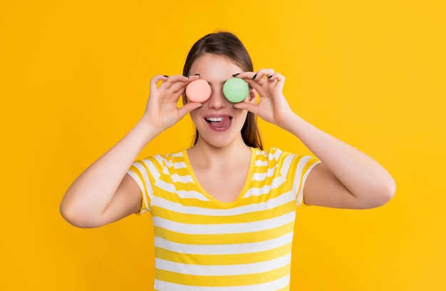 Jeune fille positive avec macaron sur fond jaune