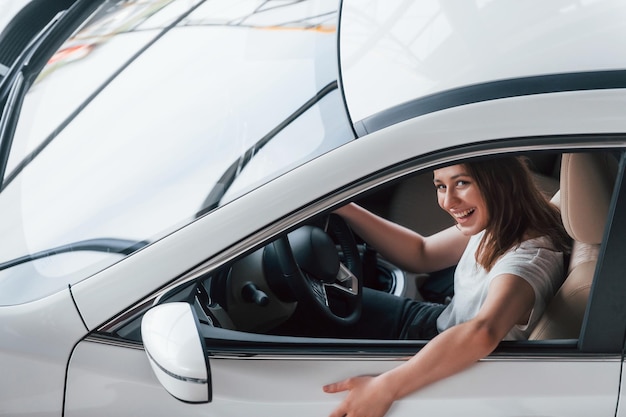 Une jeune fille positive rend visite à un salon de l'auto et choisit un gestionnaire de voiture pour l'aider