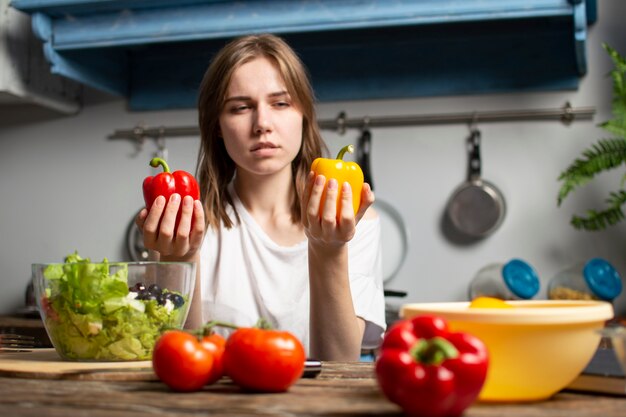 Jeune fille prépare une salade végétarienne dans la cuisine