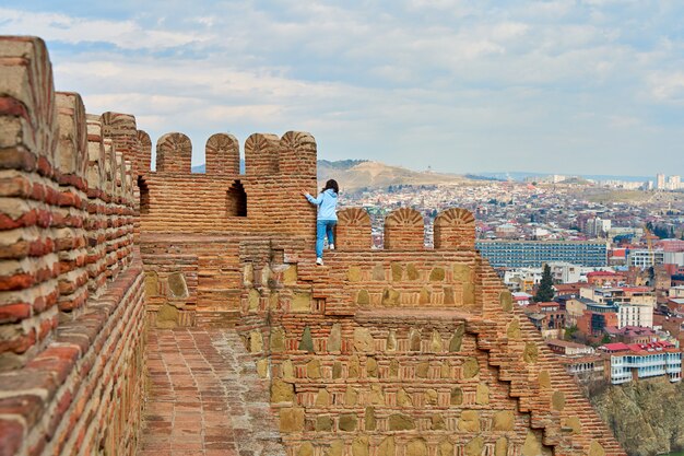 La jeune fille profite de la vue et du silence alors qu'elle est assise sur le mur d'une ancienne forteresse surplombant la ville.