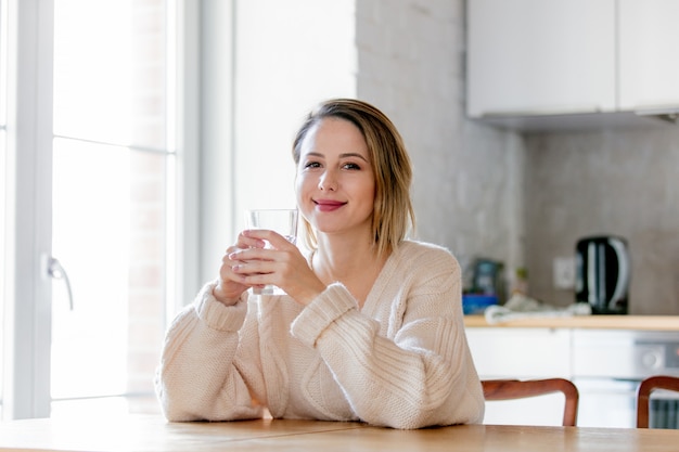 Jeune fille en pull avec un verre d'eau