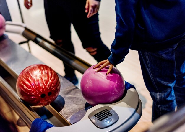 Jeune fille ramassant un concept de passe-temps et de loisirs de boule de bowling