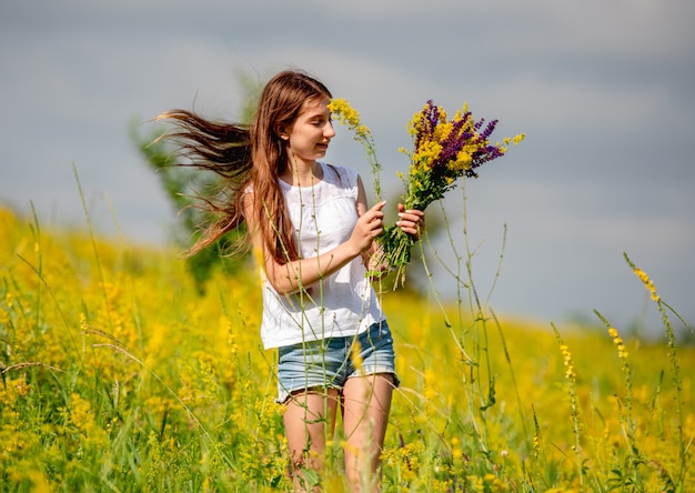 Jeune fille ramassant des fleurs sur le terrain