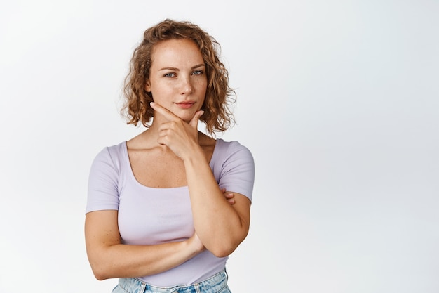 Une jeune fille réfléchie a l'air intriguée, pense à quelque chose d'intéressant, considère votre idée, reste blanche