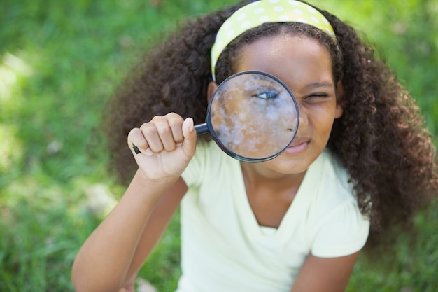 Photo jeune fille regardant à travers la loupe dans le parc