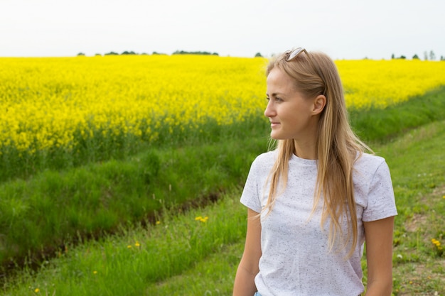 La jeune fille regarde au loin le champ jaune et le ciel bleu