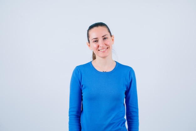 Jeune fille regarde la caméra en souriant sur fond blanc