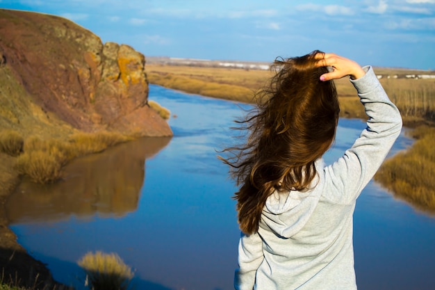 La jeune fille regarde l'eau et redresse ses cheveux flottants sur fond de t...