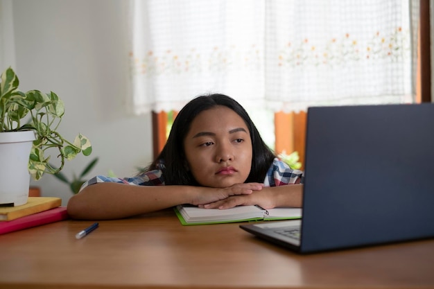 Jeune fille regarde un ordinateur portable Fille paresseuse étudiant à la maison