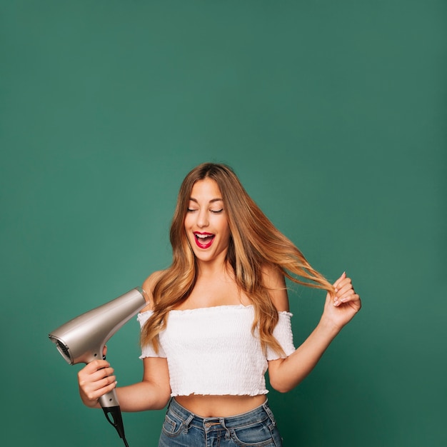 Photo jeune fille rire avec sèche-cheveux