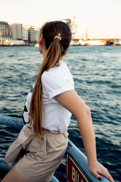 Jeune fille sur le rivage face à la mer sans visage