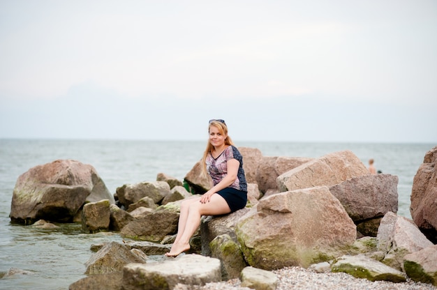 Jeune fille sur les rochers dans la mer