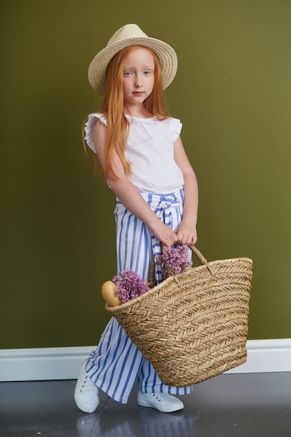 Jeune fille rousse au chapeau de paille avec de beaux cheveux longs et de grands yeux bleus