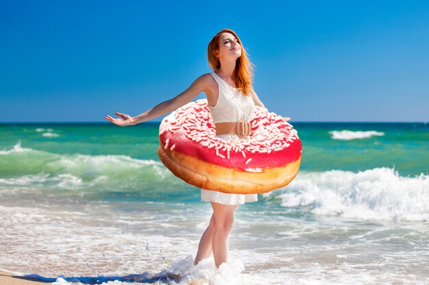 Jeune fille rousse avec un beignet à la taille