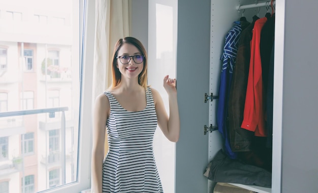 Jeune fille rousse choisissant un vêtement dans une armoire.