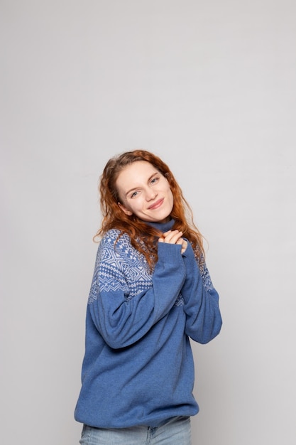 Jeune fille rousse dans un pull en tricot sur fond blanc