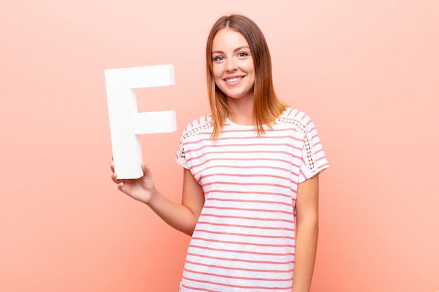 jeune fille rousse dans un T-shirt tenant la lettre f