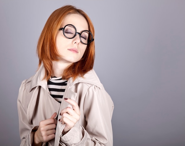 Jeune fille rousse à lunettes et manteau.