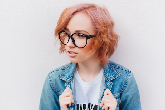 Jeune fille rousse avec des lunettes et une veste en jean