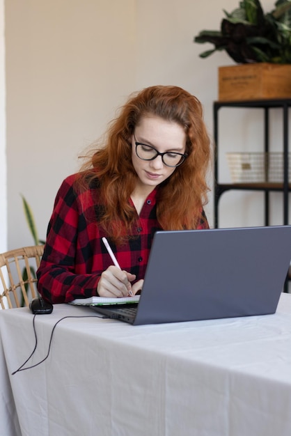 Jeune fille rousse travaille à distance de la maison