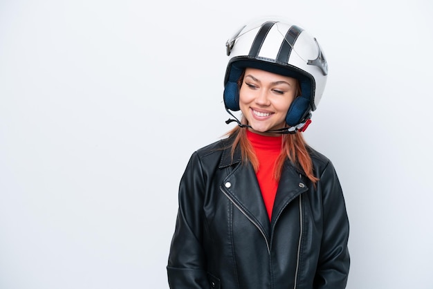 Jeune fille russe avec un casque de moto isolé sur fond blanc regardant sur le côté et souriant