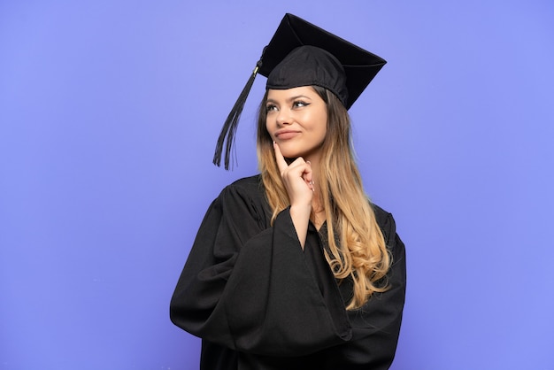 Jeune fille russe diplômée universitaire isolée sur fond blanc ayant des doutes en levant les yeux