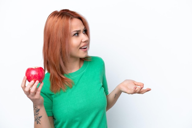 Jeune fille russe avec une pomme isolée sur fond blanc avec une expression faciale surprise