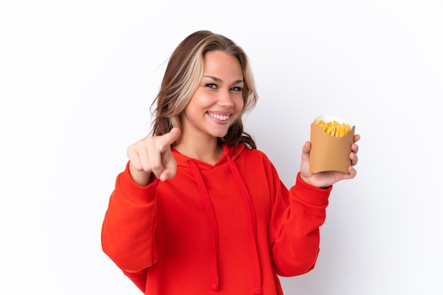 Jeune fille russe tenant des chips frites isolées sur fond blanc pointant vers l'avant avec une expression heureuse