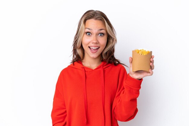 Jeune fille russe tenant des frites frites isolées sur fond blanc avec une expression faciale surprise