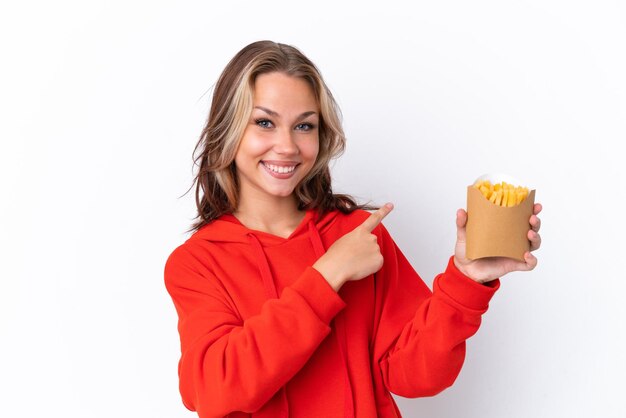 Jeune fille russe tenant des frites frites isolées sur fond blanc pointant vers l'arrière