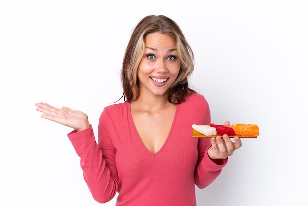 Jeune fille russe tenant sashimi isolé sur fond blanc avec une expression faciale choquée