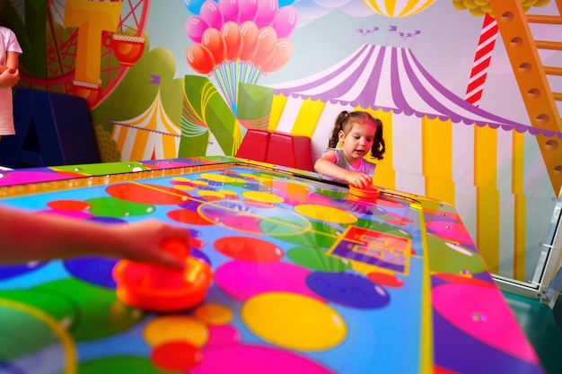 Une jeune fille s'amuse à jouer à un jeu de société coloré dans une salle de jeux animée.