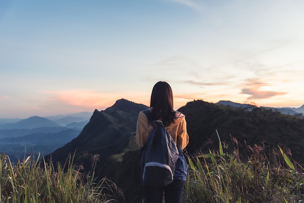 Jeune fille avec sac à dos en appréciant le lever du soleil sur la montagne