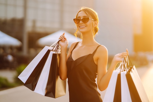 Jeune fille avec des sacs colorés se promenant dans la ville après le shopping.