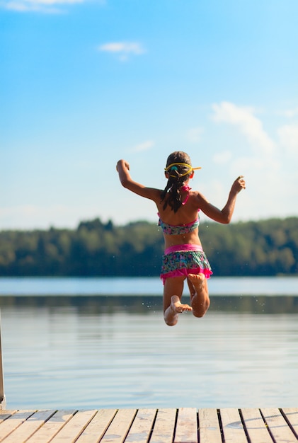 Jeune fille sautant dans l'eau, heure d'été