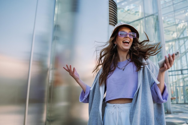 Jeune fille sautant avec un téléphone portable à la main cool femme heureuse s'amuser avec une photo de haute qualité