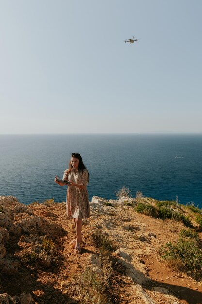 Une jeune fille se filme avec un drone près de la mer.