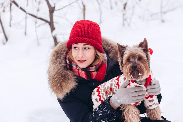 Jeune fille se promène dans les bois inférieurs en hiver avec un chien portant un pull de Noël