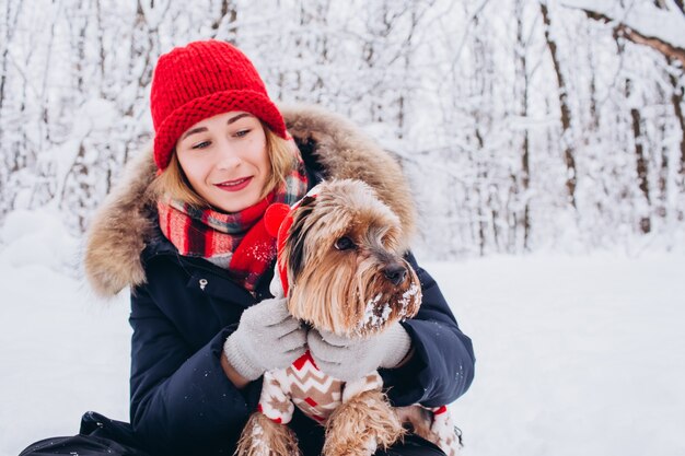 Jeune fille se promène dans les bois inférieurs en hiver avec un chien portant un pull de Noël