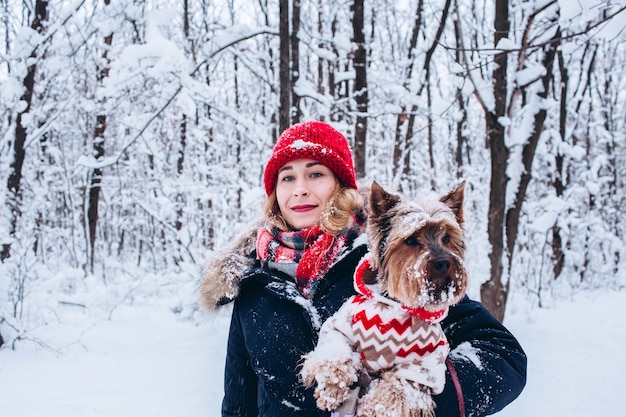 Jeune fille se promène dans les bois inférieurs en hiver avec un chien portant un pull de Noël