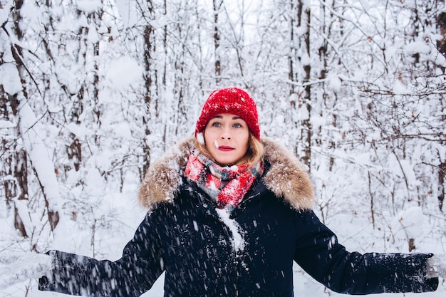 Une jeune fille se promène dans une forêt d'hiver enneigée