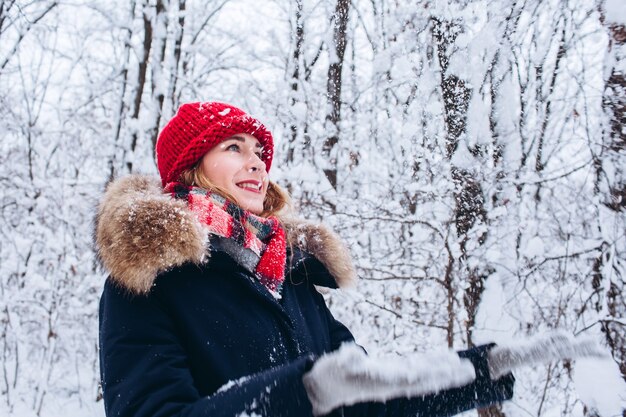 Une jeune fille se promène dans une forêt d'hiver enneigée