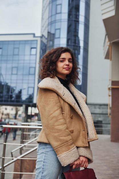 Une jeune fille se promène à l'extérieur de la ville près d'un bâtiment commercial