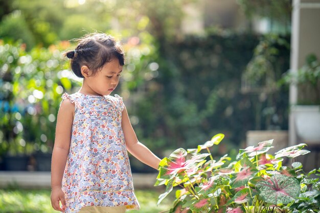 Une jeune fille se tient dans un jardin en regardant des fleurs.