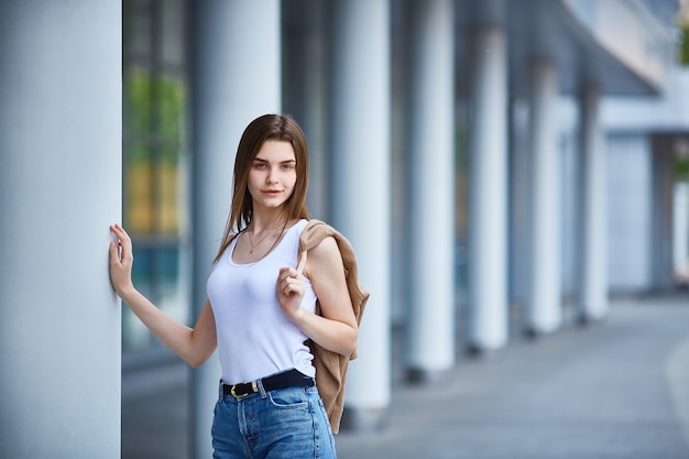 Jeune fille se tient près du bâtiment et regarde dans le cadre.