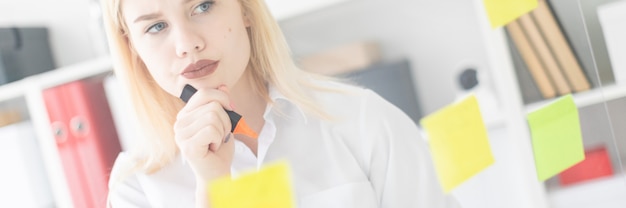 Une jeune fille se tient près d'une planche transparente avec des autocollants