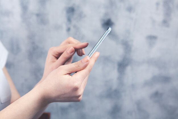 Une jeune fille se tient avec un téléphone