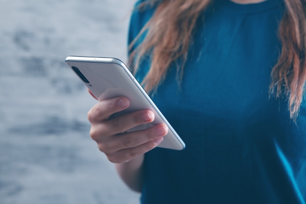 Une jeune fille se tient avec un téléphone