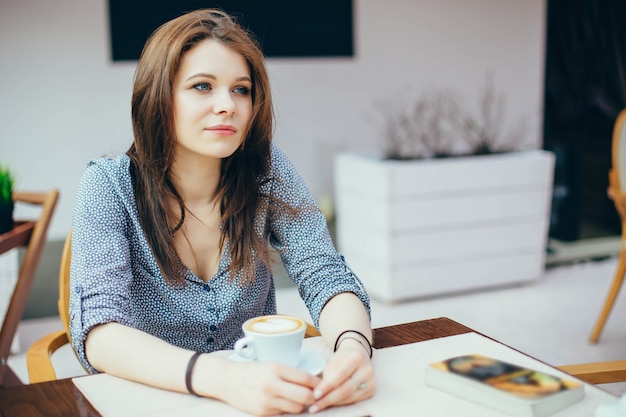 Jeune fille séduisante boit du café dans un café de la ville.